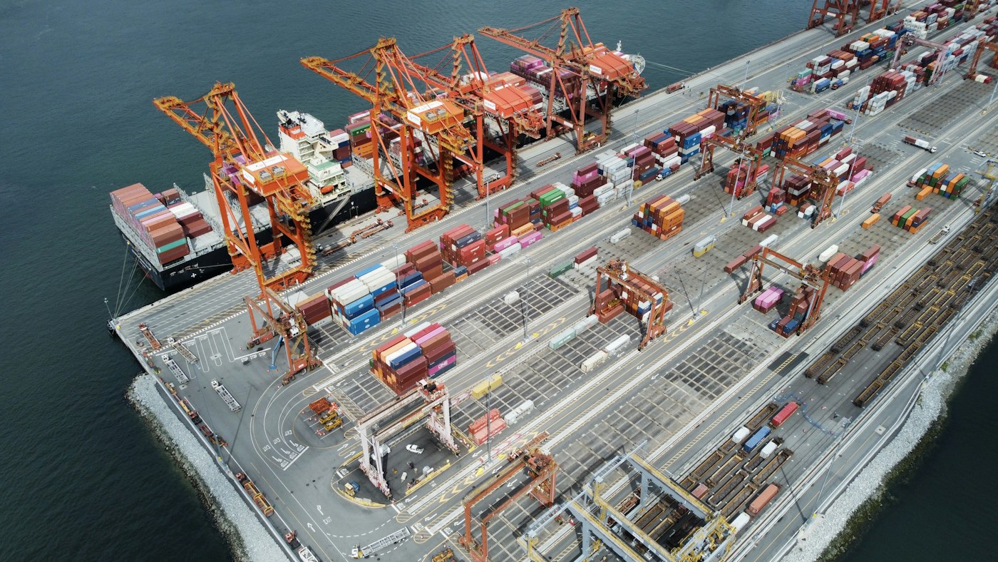 An aerial view of cranes, containers and a cargo ship at a port